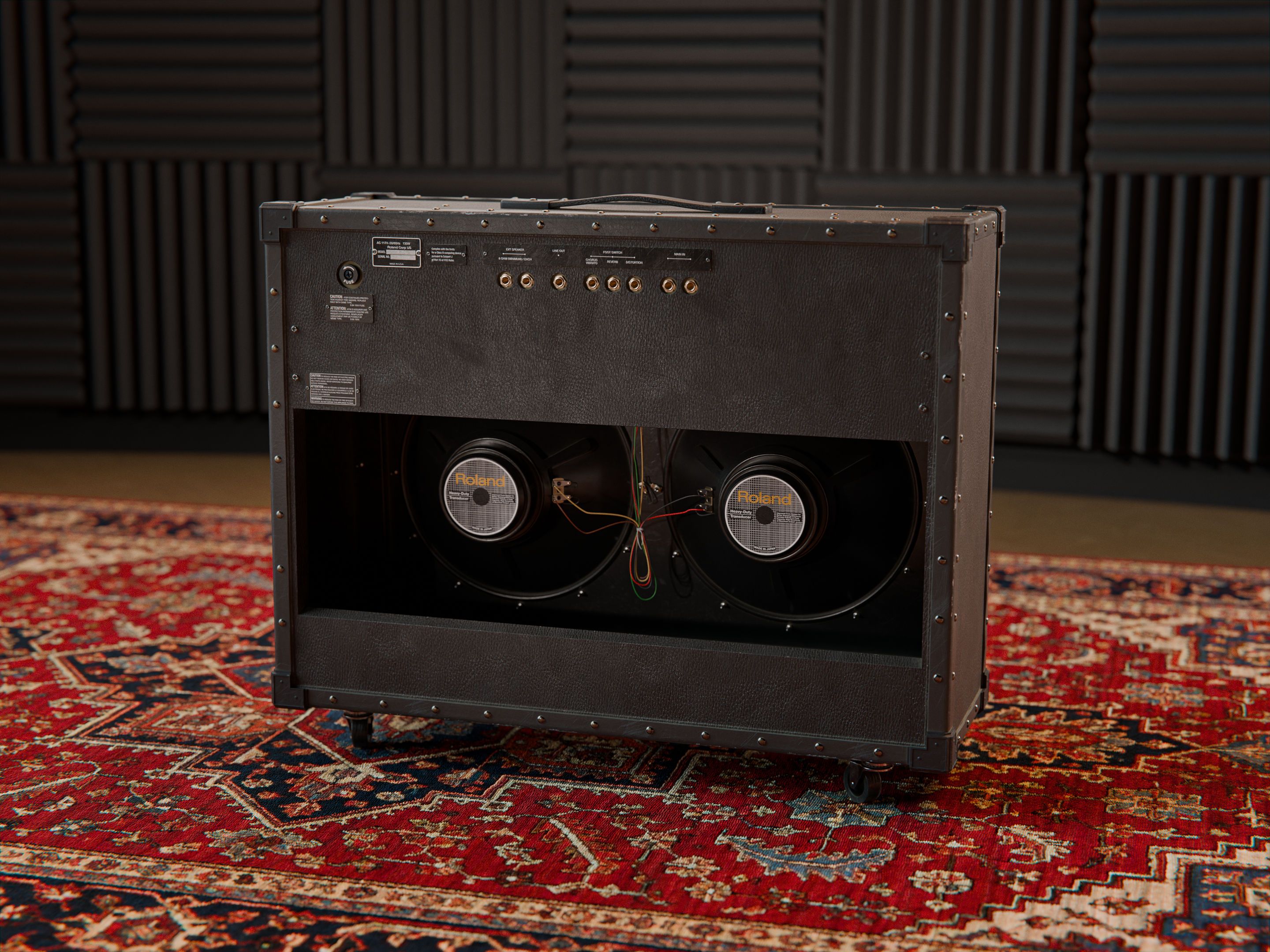 The back of the JC-120, with the back of the speakers visible, standing on a persian carpet in front of acoustic panels.